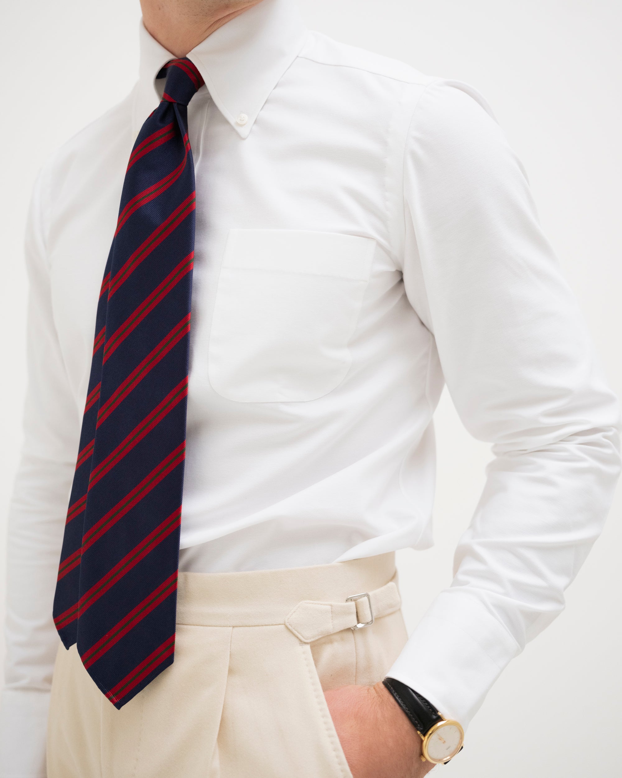 Man wearing a white OCBD, cream flannels and a Navy Red and Green Regimental Stripe Repp Tie